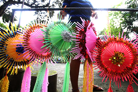 With 22 days before Christmas, a woman inspects a handmade lantern crafted from disposable straws in their compound on Wednesday, December 3. She said they created the décor to help bring the Christmas spirit to the community.