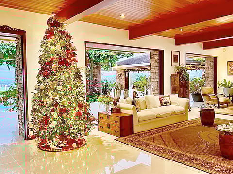 A chic and elegant take with its white sofa contrast to the red pillows and the bright christmas tree, from the Homes of Zee, home of Marguerite Lhuillier.
