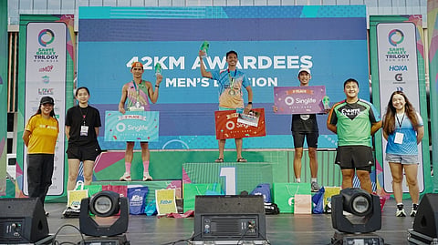 EDSEL Moral (middle) lifts the trophy after ruling the men’s 42km event of the Sante Barley Trilogy Run Asia National Finals on Saturday at the Mall of Asia Complex.