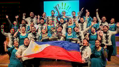 The University of Santo Tomas Singers (USTS) proudly raises the Philippine flag as USTS founder and conductor Fidel G. Calalang, Jr. (second row, center) holds the Oak of Derry Trophy from the 13th City of Derry International Choir Festival in Northern Ireland.