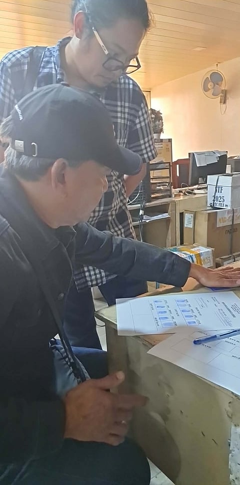 Mike Cabangon fills -up the form for his bail after a warrant of arrest was served by policemen at his home in Barangay Irisan, Baguio City on December 27, 2025. He is being charged with financing terrorism by the state. Photo Courtesy of Josie Cabangon.