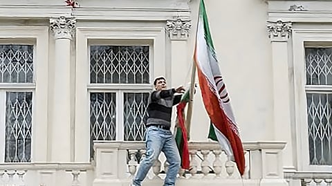 A PROTESTER replaces the Iranian flag from the balcony of Iran’s embassy with one used during the rule of the ousted shah to cheers from hundreds of demonstrators below in central London.