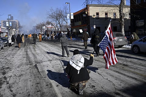 A protestor with an upside down American flag takes a knee while facing federal agents amid protests following a shooting on January 24, 2026 in Minneapolis, Minnesota. Federal agents allegedly shot and killed a protestor amid a scuffle to arrest him. The Trump administration has sent a reported 3,000 federal agents into the area, with more on the way, as they make a push to arrest undocumented immigrants in the region. 