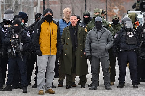 (FILES) US Customs and Border Protection Commander Gregory Bovino (C) stands flanked by fellow federal agents during a protest against ICE outside the Bishop Whipple Federal Building in Minneapolis, Minnesota, on January 15, 2026. The Department of Homeland Security denied a report on January 26 that US Border Patrol commander Gregory Bovino had been removed from his post, despite President Donald Trump reassessing harsh immigration crackdown tactics that led to the deaths of two Americans in Minneapolis. "Chief Gregory Bovino has NOT been relieved of his duties," DHS assistant secretary Tricia McLaughlin posted on X, reiterating the White House messaging that Bovino "is a key part of the President's team and a great American."