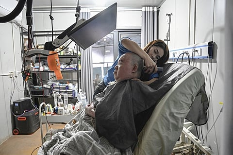 LI Qian helps her elder brother Li Xia, who has Duchenne muscular dystrophy, shave his head at their house in southwestern China’s Chongqing municipality. 