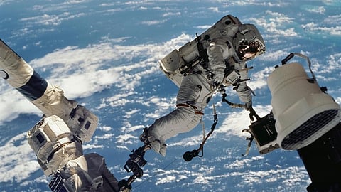 TETHERED to the void Anchored by a foot restraint on the ISS Canadarm2, astronaut David A. Wolf drifts above Earth, turning silence and vacuum into a workplace during the first extravehicular activity of the STS-112 mission.