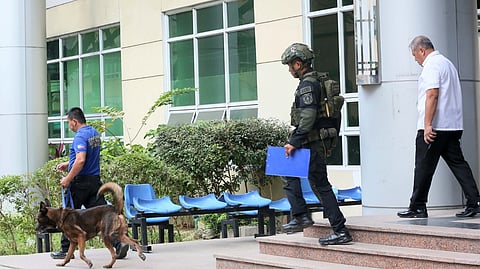 A BOMB-SNIFFING K9 is being led into the Quezon City Hall of Justice following reports of the presence of a bomb inside the building on Friday morning.