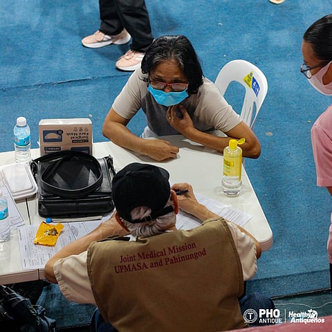 A UPMASA volunteer (below) attends to a patient during the group’s joint medical mission in San Jose de Buenavista, Antique. 