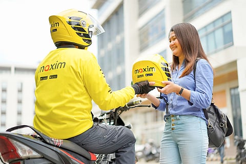 PASSENGER receives a helmet from a Maxim motorcycle taxi rider before starting a ride in Iligan City.