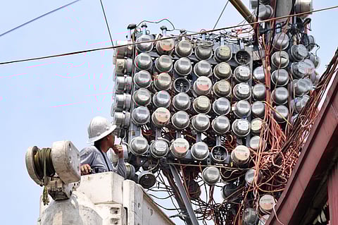 THIN margins Lineman from Manila Electric Company inspects a cluster of electric meters mounted high above a densely packed community, a measure designed to deter power pilferage. In many urban poor areas, utilities elevate meters and wiring beyond easy reach to safeguard the grid while ensuring households remain connected to electricity.