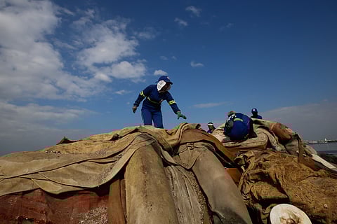Department of Environment and Public Services personnel remove broken floating barriers in Manila Bay on Saturday, 14 March 2026. The barriers, which had long been piled at the edge of Dolomite Beach, were originally used to mark the area and prevent debris from drifting further into the water.