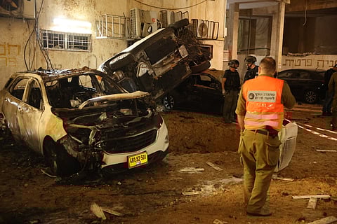 Israeli security checks the damage to cars after a rocket strike in Holon, Israel, on March 15, 2026.