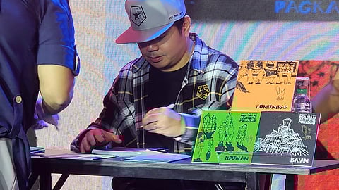 GLOC-9 signs copies of his chapbooks for readers during the launch.