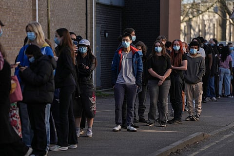 Students wearing face masks queue up to get vaccinated at the University of Kent in Canterbury, south-east England on March 18, 2026, following an outbreak of meningitis. Hundreds of masked-up students queued on March 18 to get vaccinated at the UK university campus at the heart of a deadly meningitis outbreak, as the number of cases rose to 20.