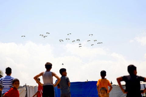 Children watch as food parcels are airdropped in Rafah in the southern Gaza Strip on August 2, 2025. Aid agencies have warned that Gaza's population is facing a catastrophic famine, triggered by Israeli restrictions on aid.