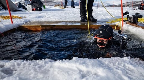 A PARTICIPANT in the Polar Scientific Diving program enters the water for a 45-minute-long diving session, at the Kilpisjaervi Biological Station in Finland on 14 March 2026. 