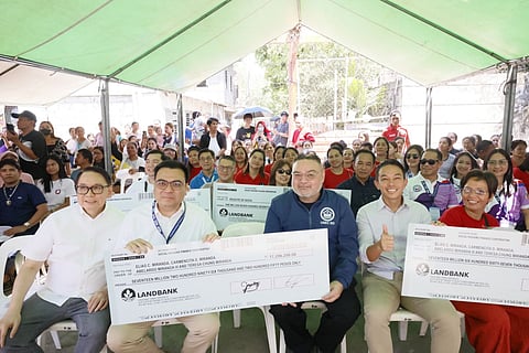 DHSUD Secretary Jose Ramon Aliling and SHFC President Federico Laxa hand over financial assistance to beneficiaries of Miranda Compound, bringing over 1,300 residents closer to land ownership. Photo courtesy of DHSUD. 
