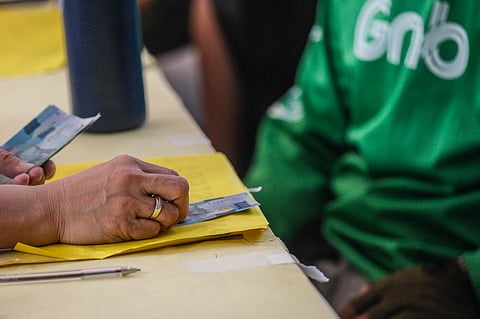 CASH lines, longer shadows Delivery riders queue at Kartilya ng Katipunan in Manila on 26 March 2026, waiting for P5,000 cash aid from the Department of Social Welfare and Development.