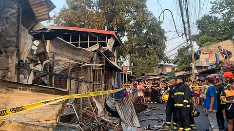 AUTHORITIES secure the fire scene at a store in Barangay Pasong Tamo in Quezon City. Reports said that at least three people were found dead. 