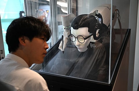 A MAN sitting before a bespectacled shaman robot that offers face-reading services to predict future prospects while sketching a portrait, at a Korean shamanism theme shop in Seoul. 
