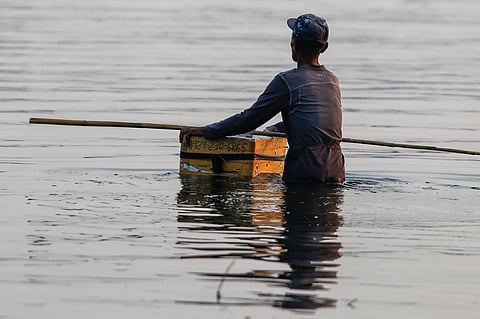 A fisherman casts his nets at a chest-deep beach in Parañaque City on Saturday. Despite the rollbacks in fuel costs, some fishermen decided not to use their motorized boats and instead use alternative methods in fishing for daily sustenance.