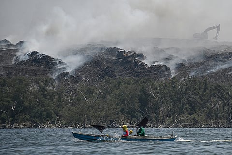 Air pollutant Obando, Bulacan fishermen  sail past smoke billowing from a landfill in Navotas City which burns 15 meters below the surface, releasing a toxic brew of methane and carbon dioxide.