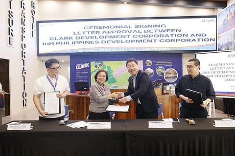 CLARK Development Corp. president and CEO Agnes VST Devanadera (second from left) and JnH Philippines Development Corp. president Lee Sangte (second from right) exchange a handshake following the signing of an amended lease agreement at the Clark Visitors Center.