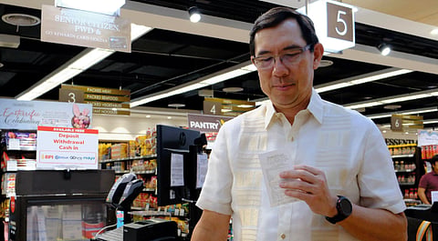 Bank of the Philippine Islands President and CEO TG Limcaoco holds the first receipt from a deposit made through a barcode transaction at The Marketplace.