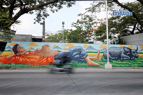(May 13 2026) Motorists passing at the mural of a Farmer resting and his Carabao along Pulilan regional Road, Pulilan Bulacan on Wednesday May 13 2026, an Artist tribute to San Isidro Labrador the patron saint of farmers, a day of the Pulilan Kneeling Festival a unique, annual cultural and religious event in Pulilan, Bulacan held every 14 and 15 of May to honor San Isidro Labrador. Photo/Analy Labor