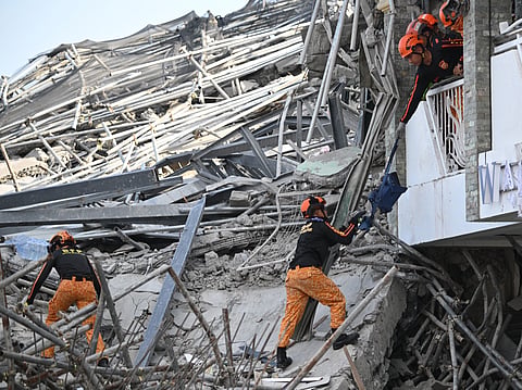 LIFELINE Rescuers pass equipment hand to hand as search operations continue at the site of a collapsed building in Angeles City, Pampanga, on Sunday. Dozens of people were feared trapped beneath the rubble of the structure, which was still under construction. 