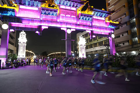 RUNNERS pass beneath the illuminated Binondo-Intramuros Bridge gateway during the Galaxy Manila Marathon.