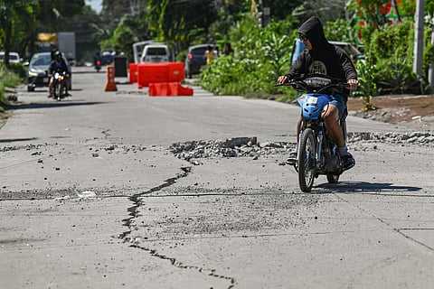 ROAD to recovery A man rides along a damaged road in General Santos City days after a magnitude 7.8 earthquake struck the area on 8 June. 
