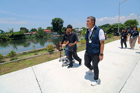 Environment Secretary Juan Miguel T. Cuna talks with teenagers who were playing with their kick scooters while walking along the riverside walkway of the Disiplina Park at Barangay Bagumbayan in Balanga City, Bataan on 17 June 2026.