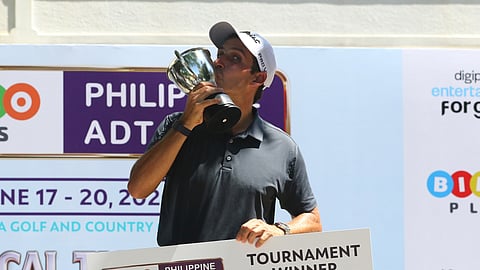 ITALIAN golfer Michele Ortolani kisses the championship trophy while holding the winner’s check after topping the Philippine ADT Open at Luisita Golf and Country Club.