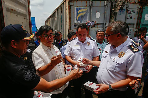 National Bureau of Investigation Director Melvin Matibag, alongside representatives from the Bureau of Customs and other agencies, leads an inspection of smuggled cigarettes at a private port in Manila on 23 June 2026. The twenty-three container vans from Cebu contained cigarettes lacking the required tax stamps, a violation confirmed by the Bureau of Internal Revenue. The seized contraband is valued at approximately ₱1.7 billion.