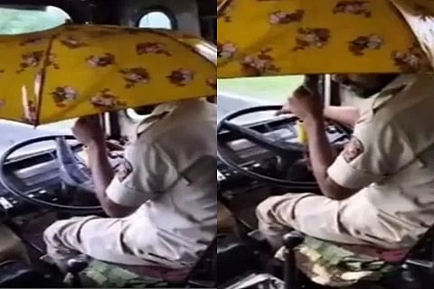 The driver drove the bus with the steering wheel in one hand and an umbrella in the other