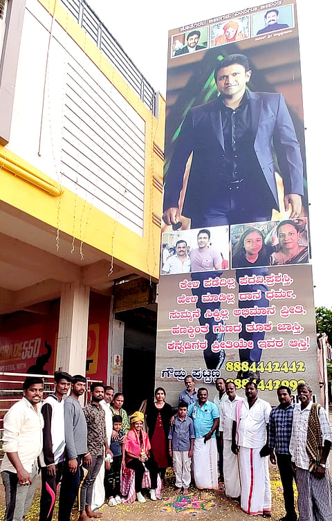  ಮೂಗೂರು ಬಸ್ ನಿಲ್ದಾಣದ ರತ್ನ ಕಂಫರ್ಟ್ ಮುಂಭಾಗದಲ್ಲಿನ 40 ಅಡಿ ಎತ್ತರದ ಅಪ್ಪು ಭಾವಚಿತ್ರಕ್ಕೆ ಗೌಡರ ಪುಟ್ಪು ರವರು ಪುಷ್ಪಾರ್ಚನೆ ಮಾಡಿದರು.