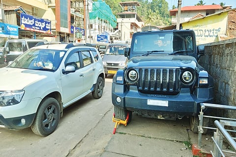 ಫುಟ್‌ಪಾತ್ ಮೇಲೆ ನಿಲ್ಲಿಸಿದ ಪ್ರವಾಸಿಗರ ವಾಹನ.