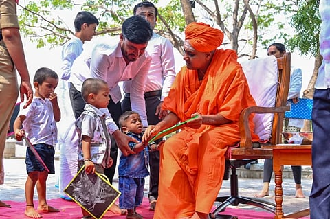 ಮಗುವಿನ ಕೈಯಿಡಿದು ಅಕ್ಷರ ಬರೆಸುತ್ತಿರುವ ಶ್ರೀಗಳು.