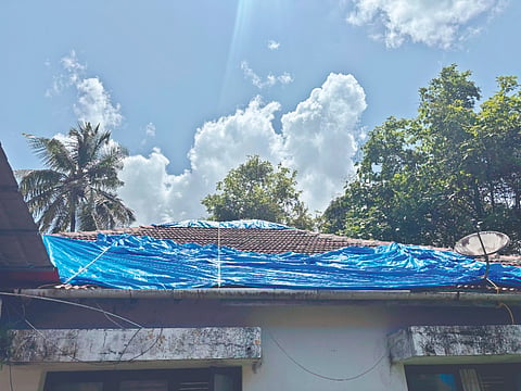  ಸೋರುತ್ತಿರುವ ಅತಿಥಿಗೃಹಕ್ಕೆ ಪ್ಲಾಸ್ಟಿಕ್ ಟಾರ್ಪಾಲಿನ ಹೊದಿಕೆ ಹಾಕಿರುವುದು.