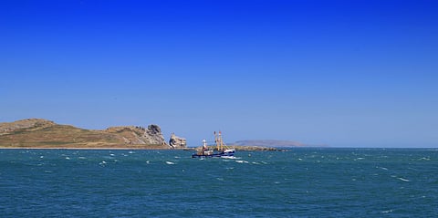 A fishing trawler passing the uninhabited island of Ireland's Eye off Howth Harbour in Dublin Bay, Ireland.