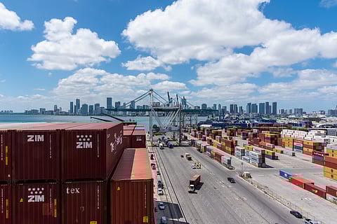 Miami, Florida, USA - view on the containers loaded on the cargo ship and on the port terminal with gantry cranes and stored containers in the background.