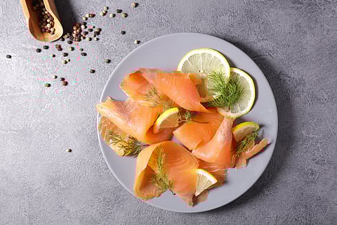 Smoked salmon on a plate with dill and lemon slices.
