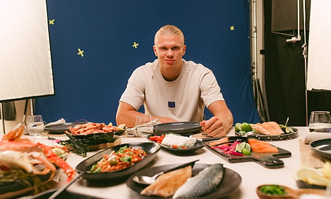 Erling Haaland sitting at a table in front of different Norwegian seafood products.