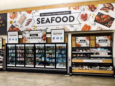Fresh and frozen Seafood selection at an American grocery store supermarket. Seafood department sign above retail display.