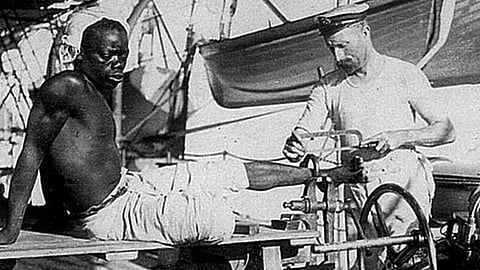 A Royal Navy sailor removes iron restraints from a newly liberated slave
