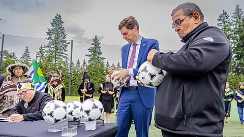 B.C. Premier David Eby signs soccer balls with local indigenous leaders in Vancouver June 27. B.C. will host seven World Cup soccer matches next year, at a cost currently estimated at about $600 million 