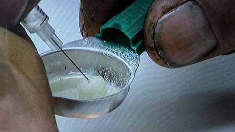 An addict  prepares a drug injection at the Sheldon Chumir Safe Consumption Site in Calgary