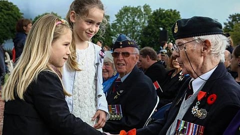 Canadian Veterans of D-Day and the Battle of Normandy, Fraser Muir and Roy Eddy, receive thanks and poppies from French children as part of a ceremony at the Brettville-sur-Laize Canadian War Cemetery in France, on the 70th anniversary of the landings in June 2014.