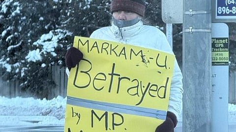 A protestor holding a sign saying that MP Michael Ma betrayed his constituents